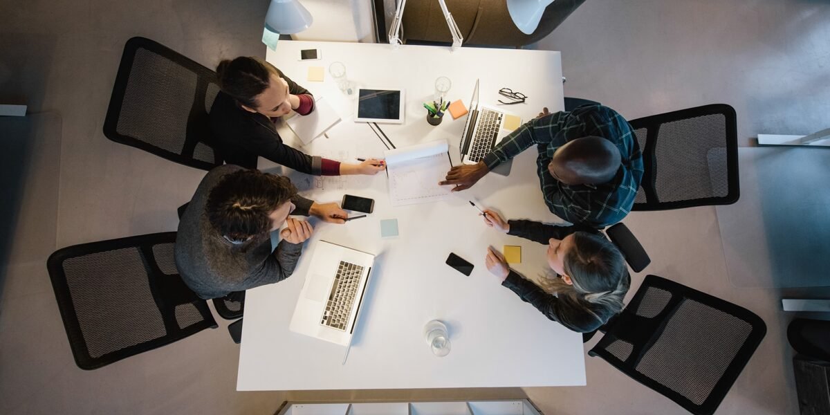 Office workers gather around a table to do research and implement new ideas. High angle view of multi-ethnic business people discussing in board room meeting